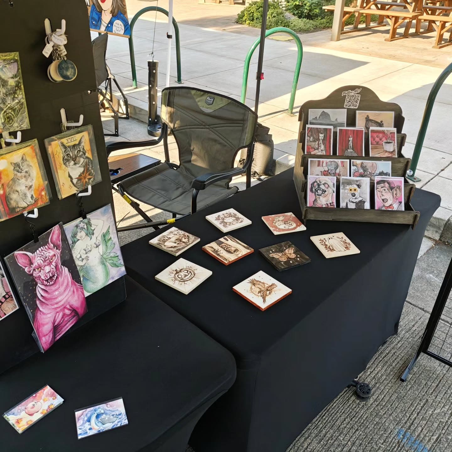 The Paint and Pyre market table with prints and pyrography pieces displayed